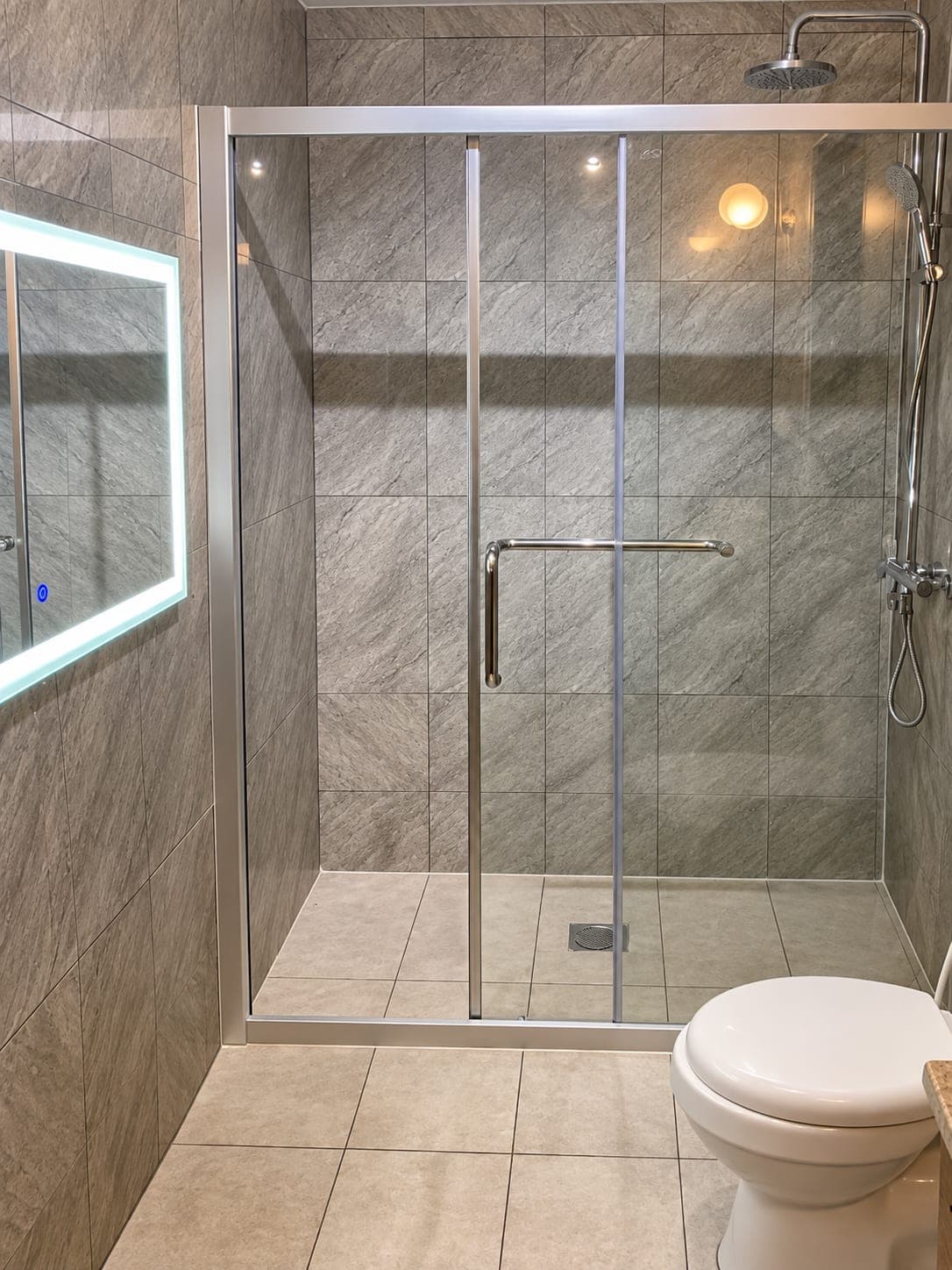 A stone-tiled shower with a glass door