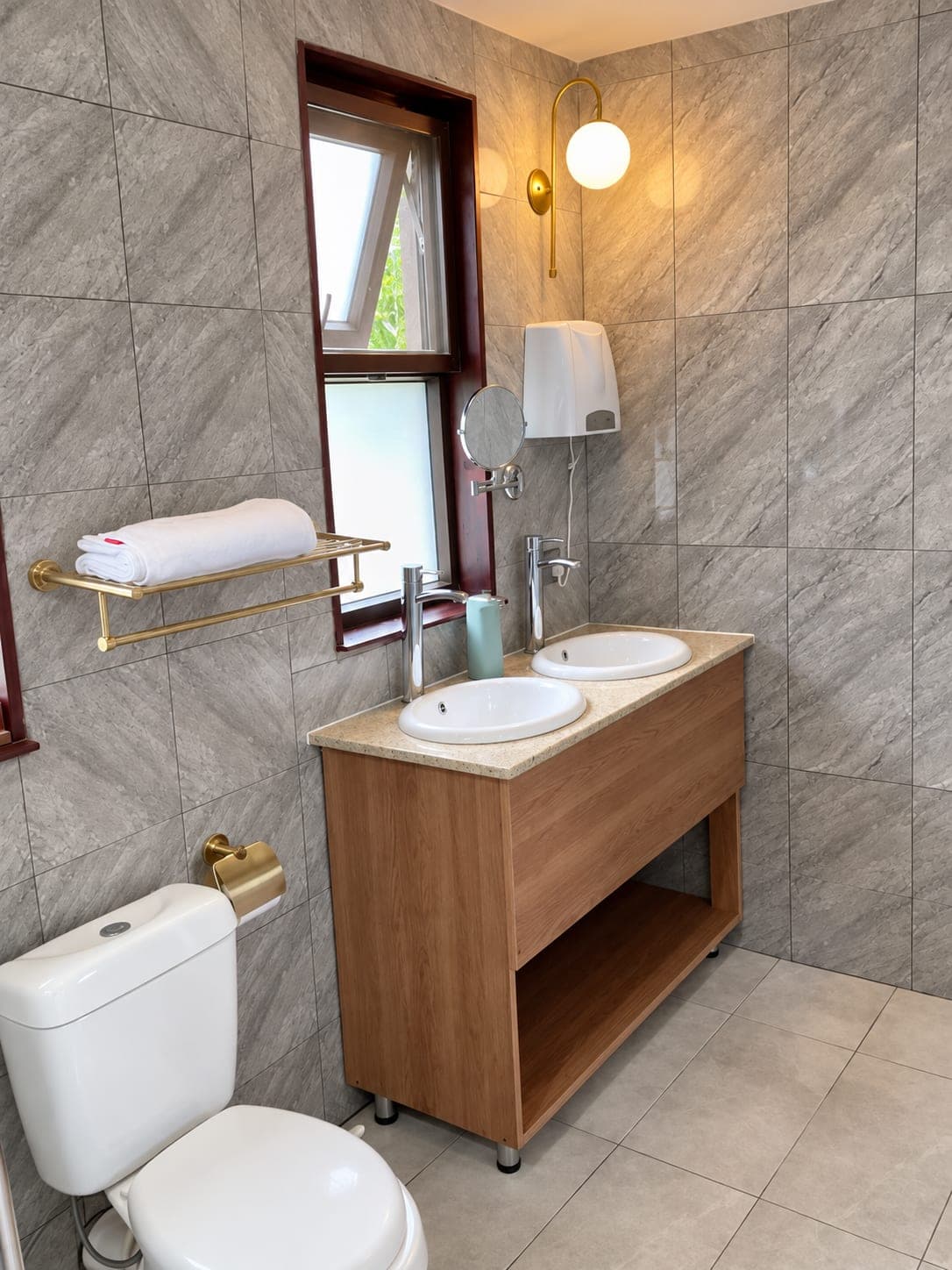 A bathroom with a twin stone vanity and warm lamp light