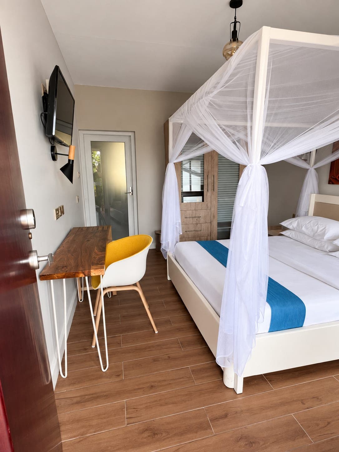 A cottage bedroom with a timber desk and a mosquito net over the bed