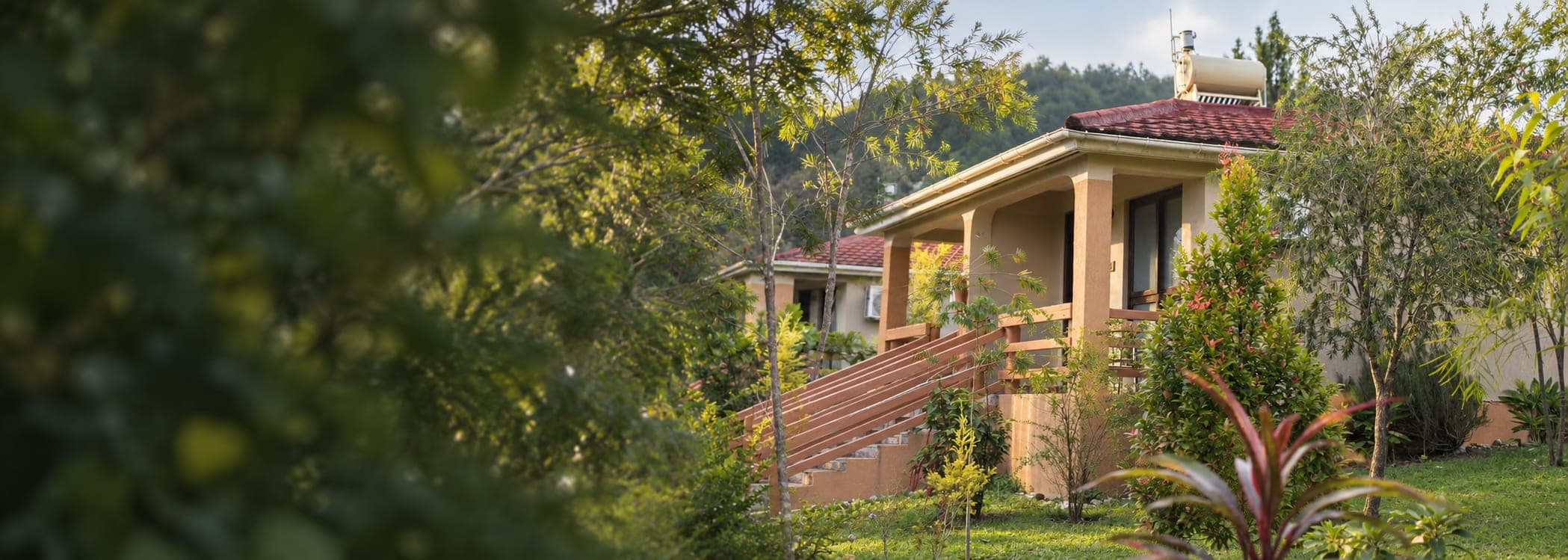 A Zebi Ecolodge cottage with a porch, set in gardens outside Hoima